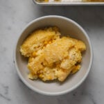 A small bowl of cornbread pudding on a marble tabletop.