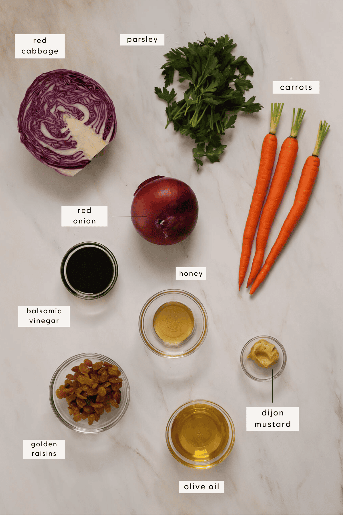 Recipe ingredients individually portioned and labeled; carrots, half a red cabbage, golden raisins, balsamic vinegar.