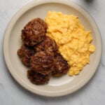 A platter of scrambled eggs and breakfast sausage patties.