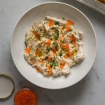 A white bowl of smoked fish dip topped with minced chives and fish roe.