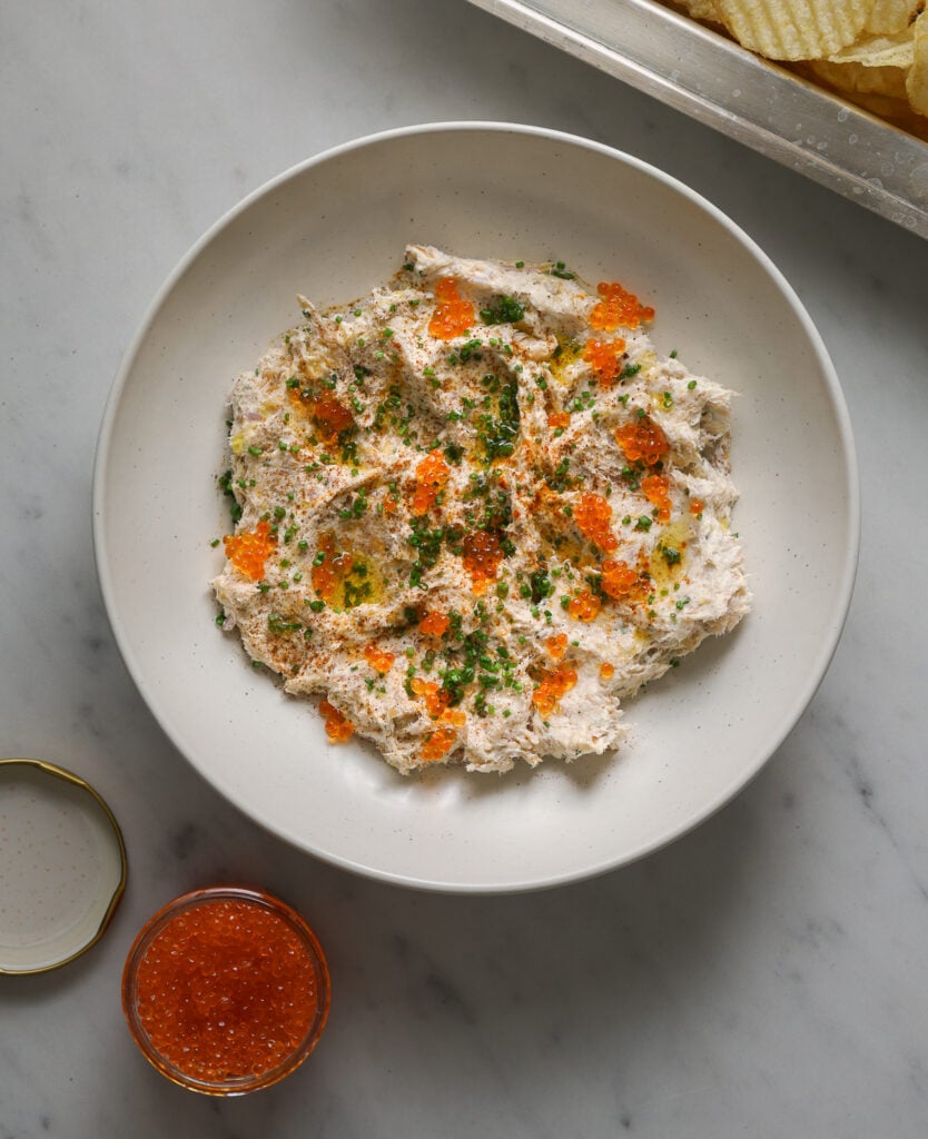 A white bowl of smoked fish dip topped with minced chives and fish roe.