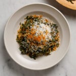 A bowl of Kale Caesar Salad on a white marble table top.